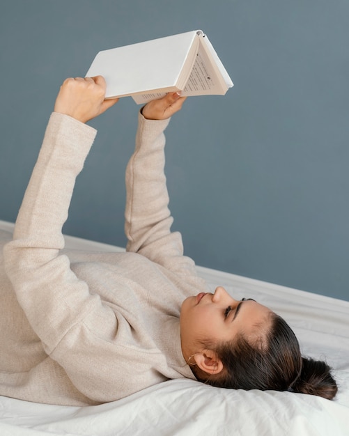 Средний снимок женщины, читающей в постели