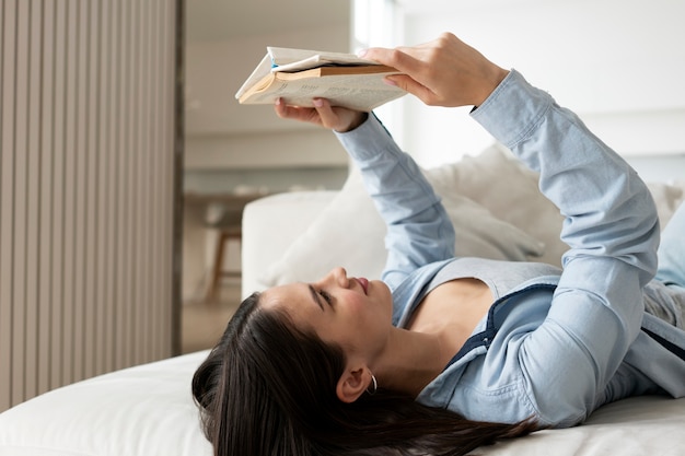중간 샷 여자 독서 모드 침대