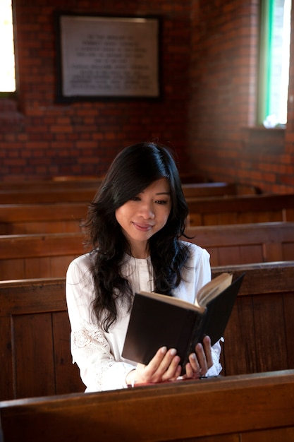 Foto gratuita donna del colpo medio che legge la bibbia in chiesa