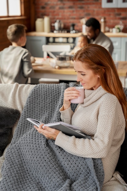 Medium shot woman reading on couch