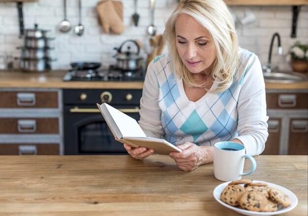 Medium shot woman reading in the kitchen