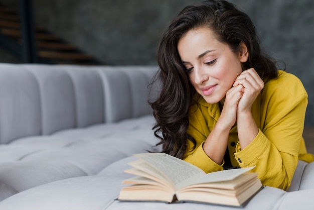 Free photo medium shot woman reading in the living room