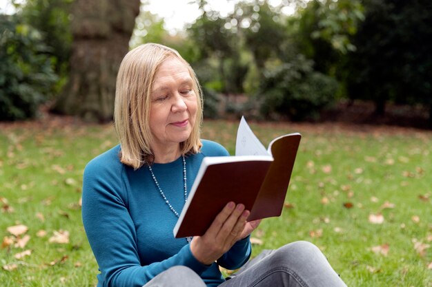 Medium shot woman reading in nature