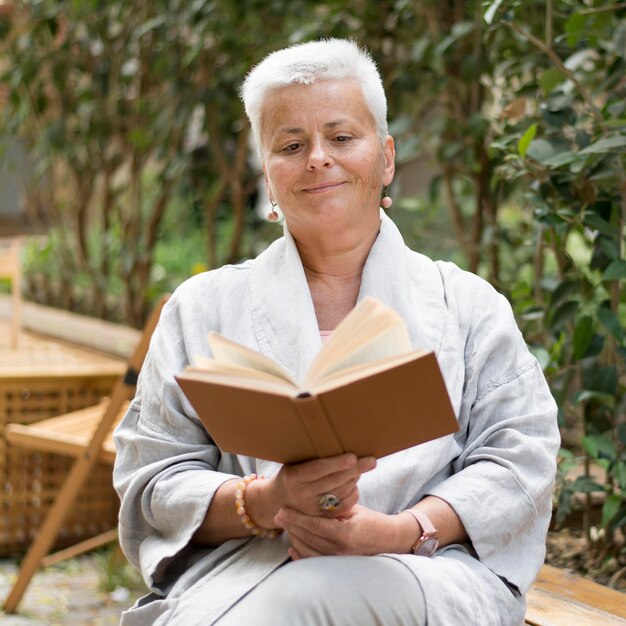 屋外で読書をするミディアムショットの女性