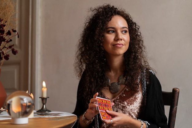 Free photo medium shot woman reading tarot at table