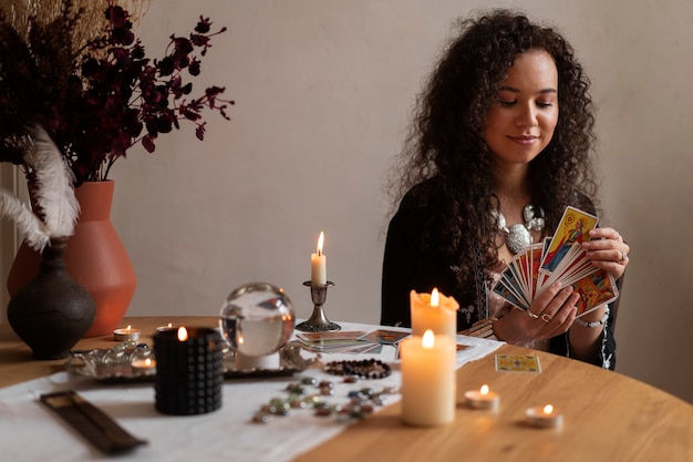 Medium shot woman reading tarot at table