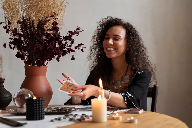 Medium shot woman reading tarot at table