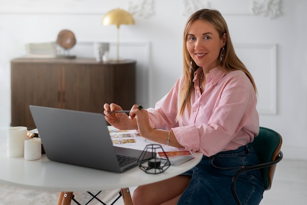 Medium shot woman reading tarot with laptop