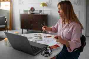 Foto gratuita donna del colpo medio che legge tarocchi con il computer portatile