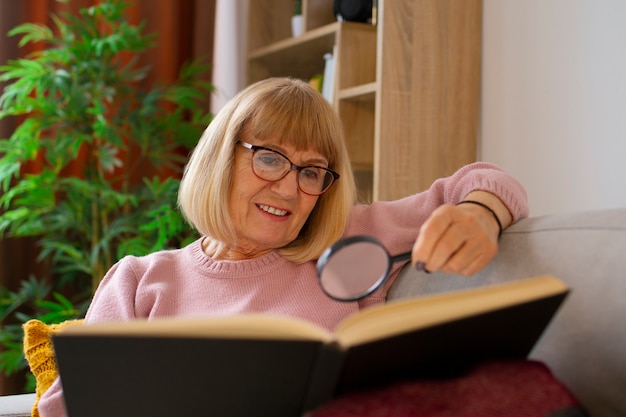 Free photo medium shot woman reading with magnyfier