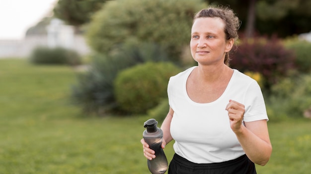 Foto gratuita donna del colpo medio che corre all'aperto