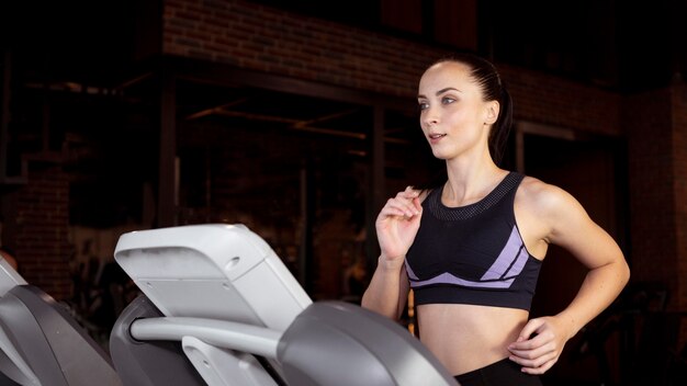 Medium shot woman running on treadmill