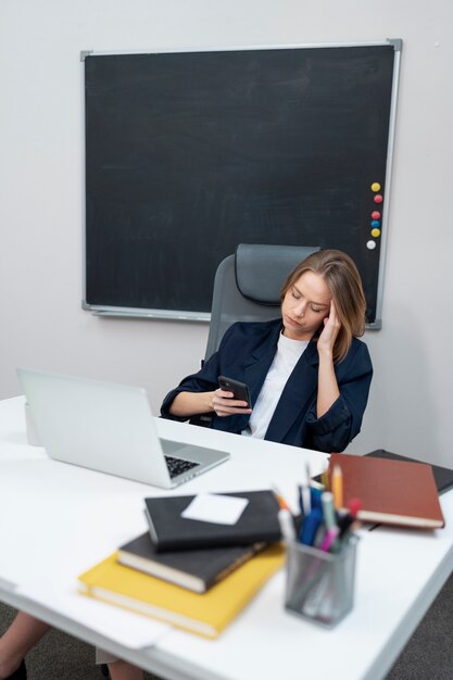 Medium shot woman scrolling on phone at work