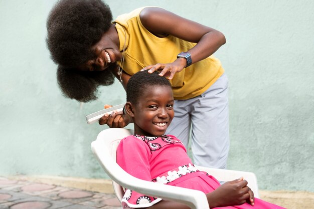 Medium shot woman shaving girl's hair