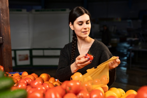 유기농 토마토를 쇼핑하는 중형 여성