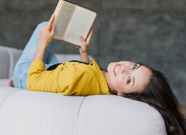 Free photo medium shot woman sitting on her back with book