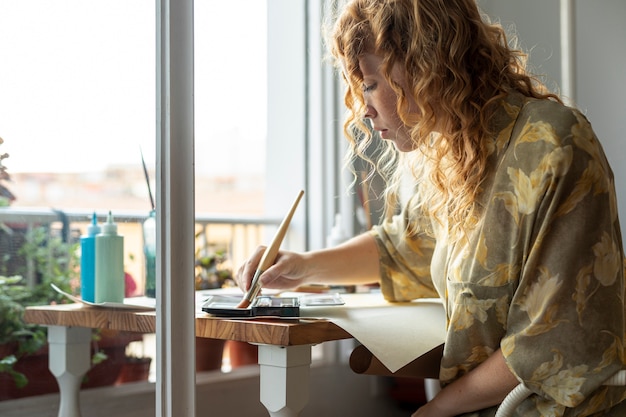 Free photo medium shot woman sitting and painting