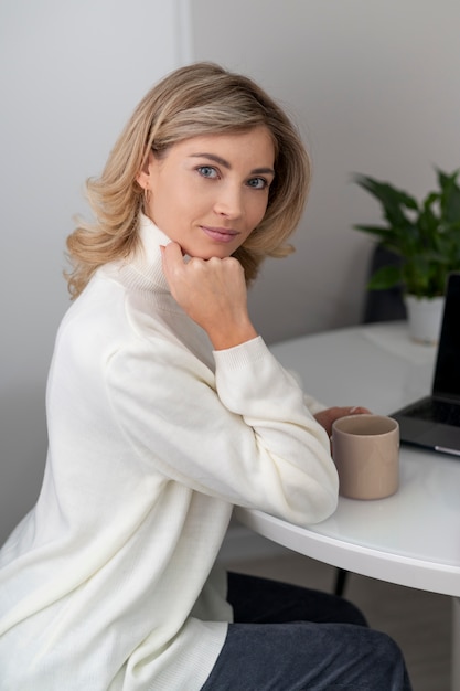 Free photo medium shot woman sitting with cup