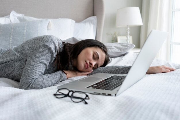Medium shot woman sleeping near laptop