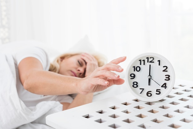 Medium shot woman sleeping with clock