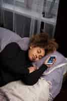 無料写真 携帯電話を手に寝ているミディアムショットの女性