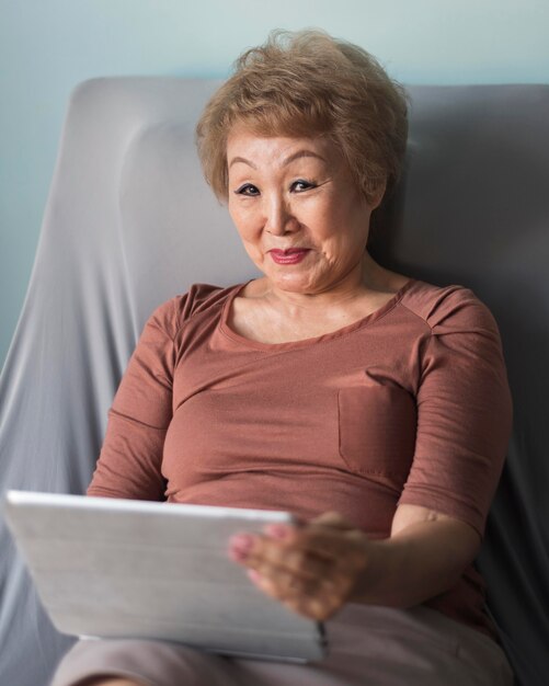 Medium shot woman on sofa holding tablet