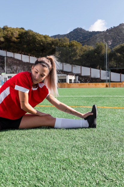 Medium shot woman stretching leg on field