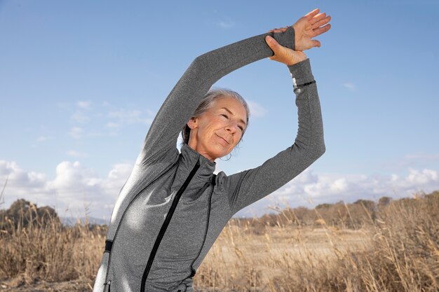 Medium shot woman stretching outdoors