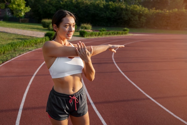 Free photo medium shot woman stretching outdoors