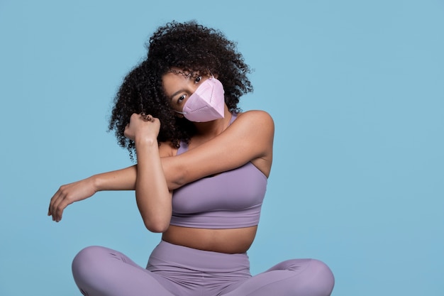 Medium shot woman stretching with mask