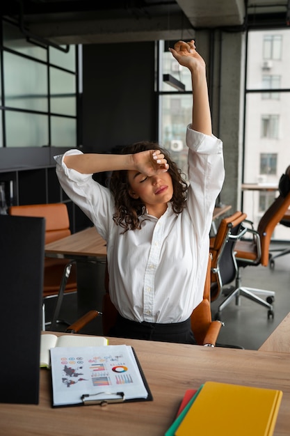 Free photo medium shot woman stretching at work