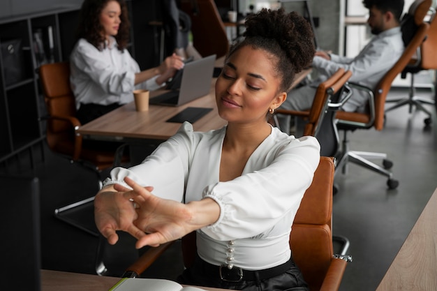 Free photo medium shot woman stretching at work