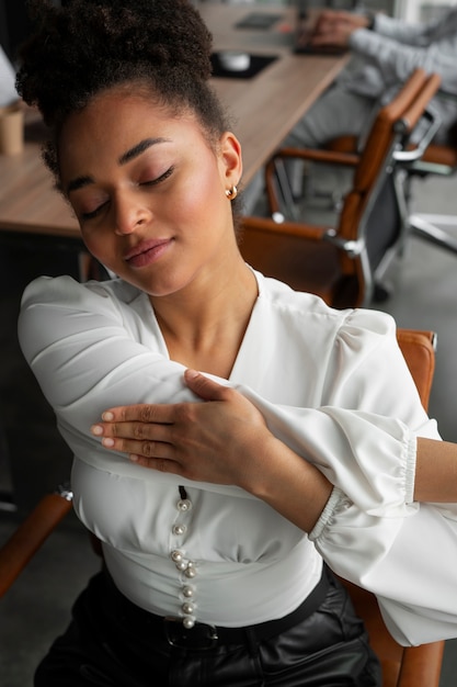 Free photo medium shot woman stretching at work