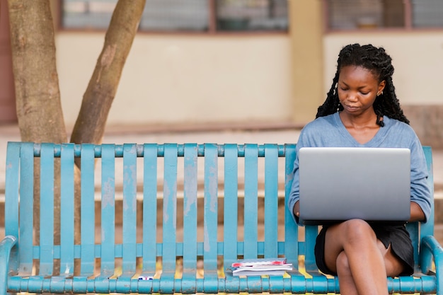 Foto gratuita donna del colpo medio che studia con il computer portatile