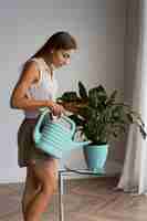 Бесплатное фото Среднего выстрела женщина заботится о растении