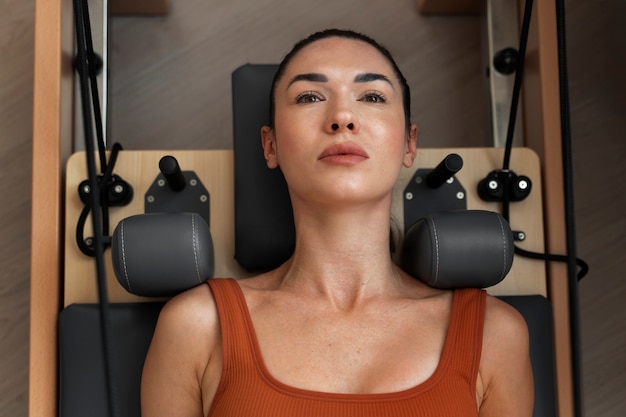 Foto gratuita donna media che prende un corso di pilates per riformatori.