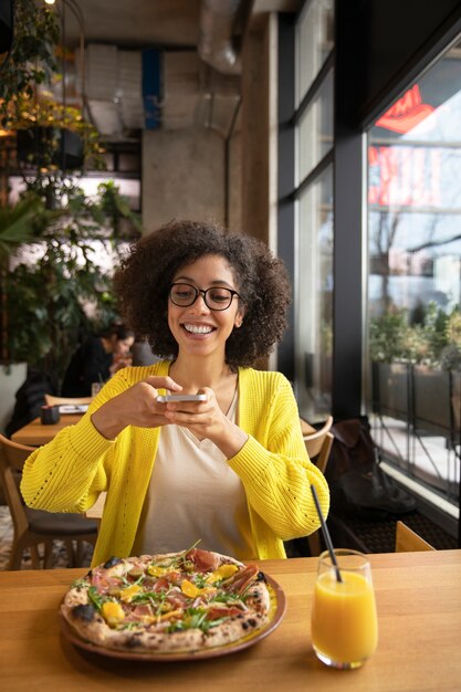 medium shot woman taking pizza photo