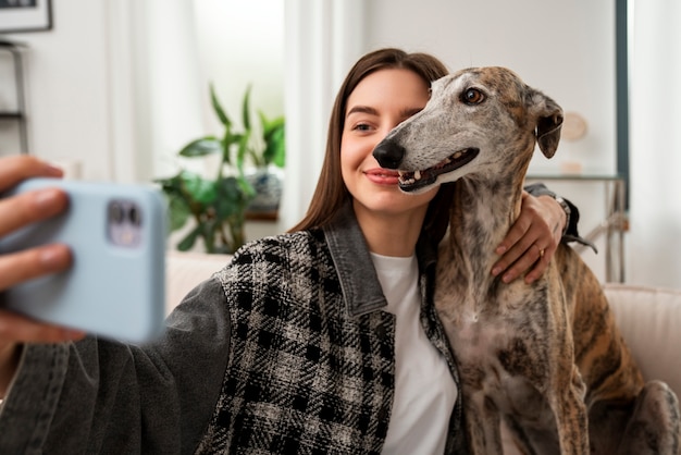 Foto gratuita donna del colpo medio che prende selfie con il cane