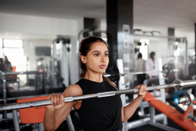 Foto grátis mulher de tiro médio treinando com barra