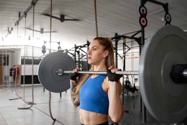 Medium shot woman training with barbell