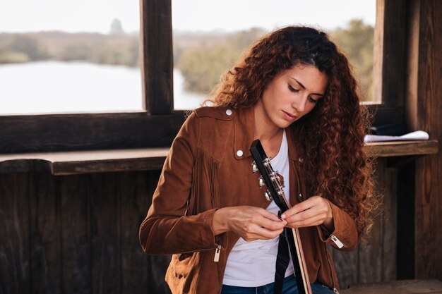 Medium shot woman tuning a guitar