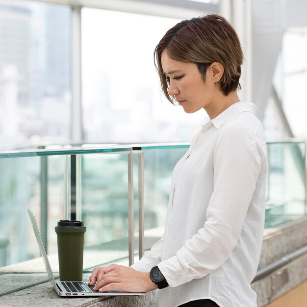 Donna del colpo medio che digita sul computer portatile