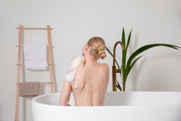 Medium shot woman using bath sponge