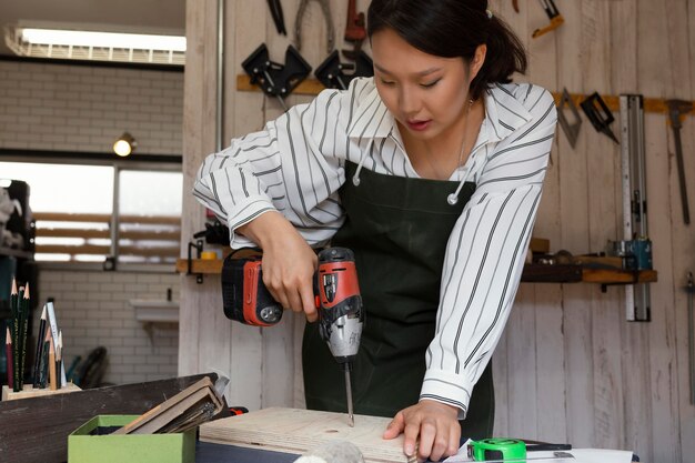 Medium shot woman using drill