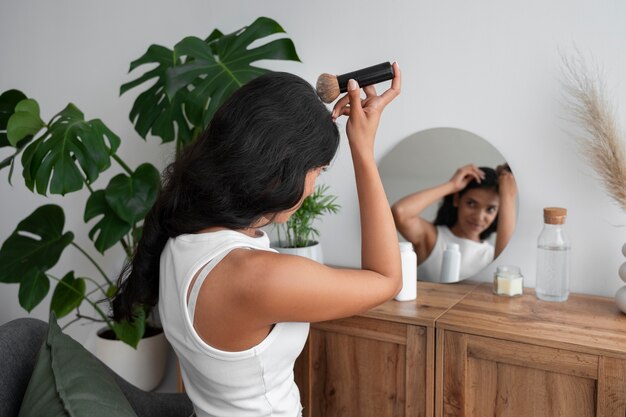 Medium shot woman using dry shampoo at home