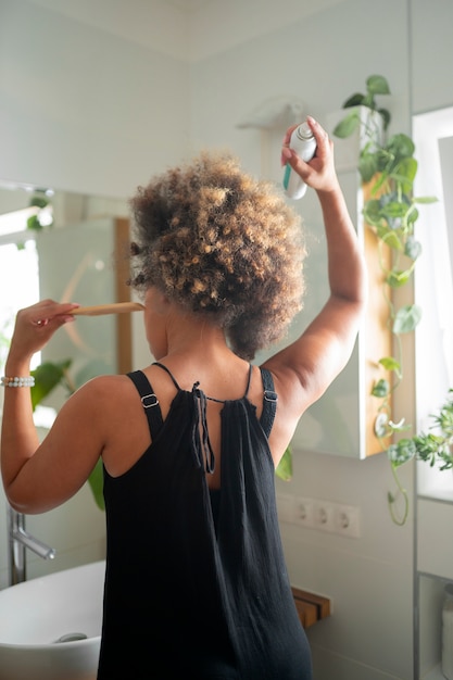 Free photo medium shot woman using dry shampoo