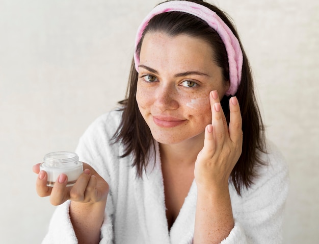 Free photo medium shot woman using face cream