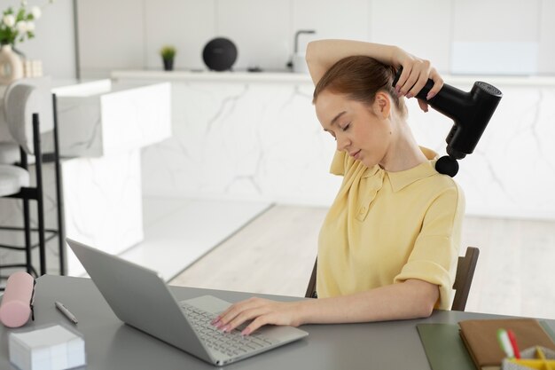 Medium shot woman using massage gun