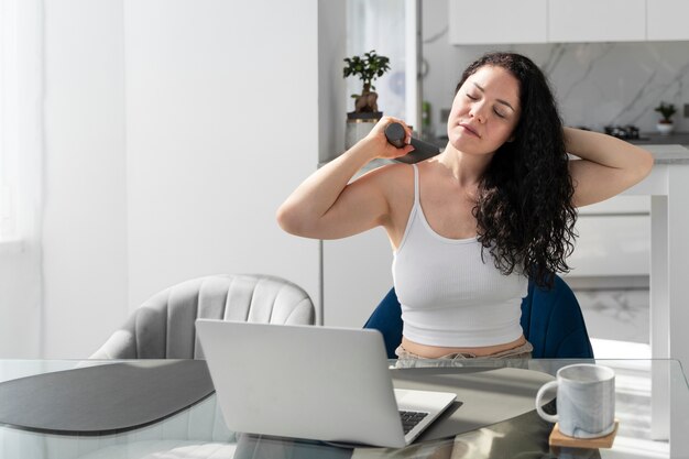 Medium shot woman using massage gun