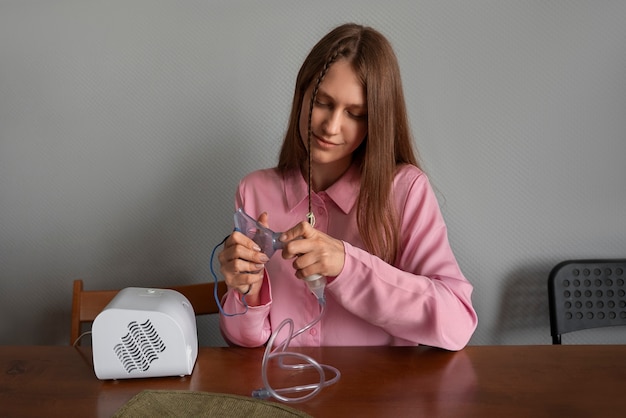 Free photo medium shot woman using nebulizer at home